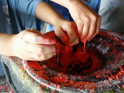 Close-up of hands squishing colorful red oobleck