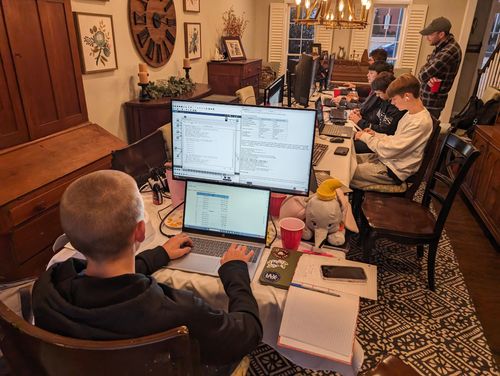 Students working a cybersecurity challenge at multiple monitors