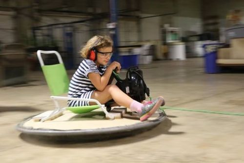 Kid riding a maker-built hovercraft