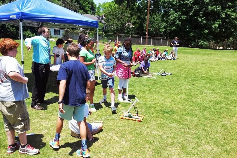 Kids gathered at a school field for a compressed air rocket launch event with Maker Lab Kids