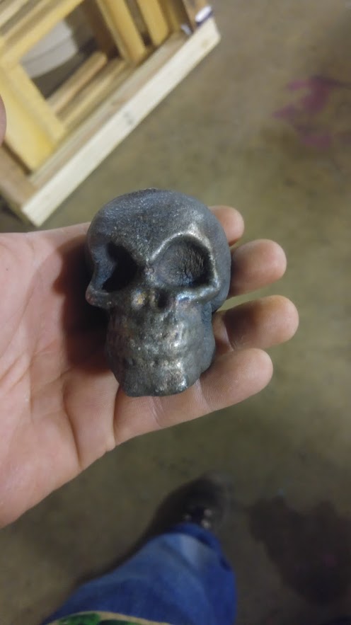 Cast aluminum skull held in hand