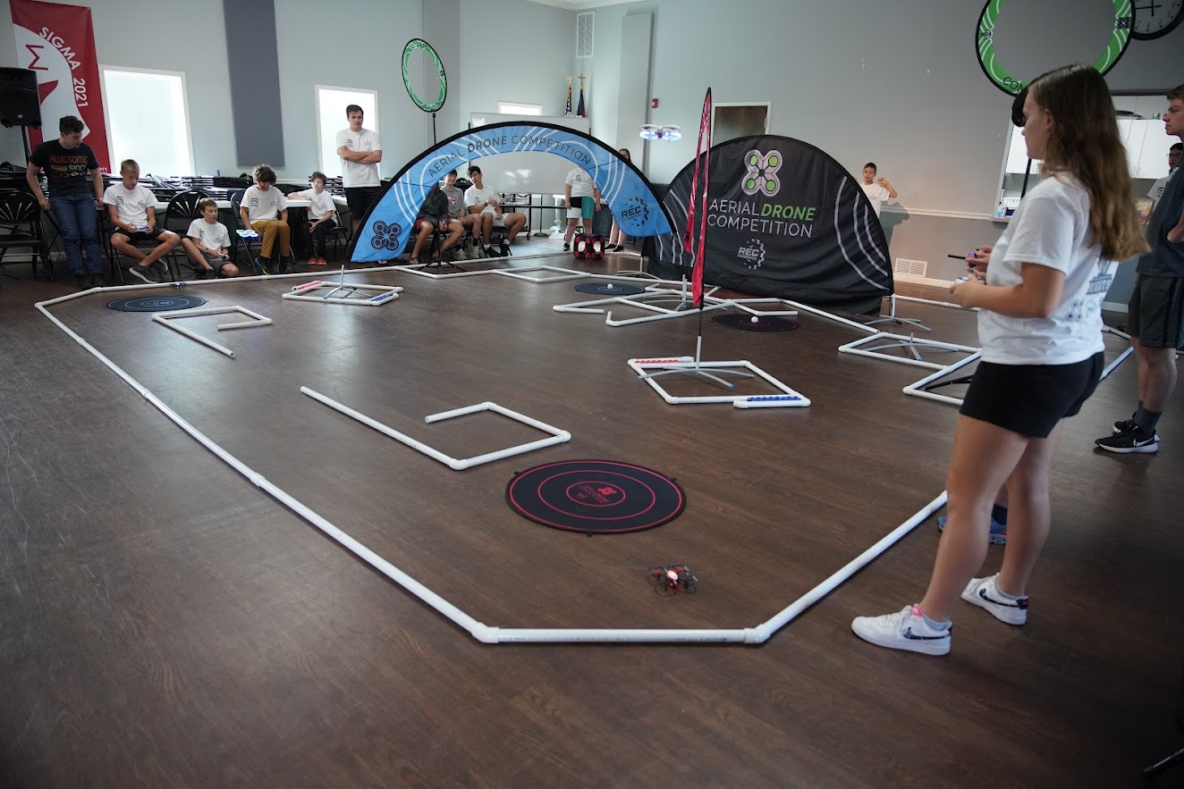 Girl piloting drone at competition with audience watching