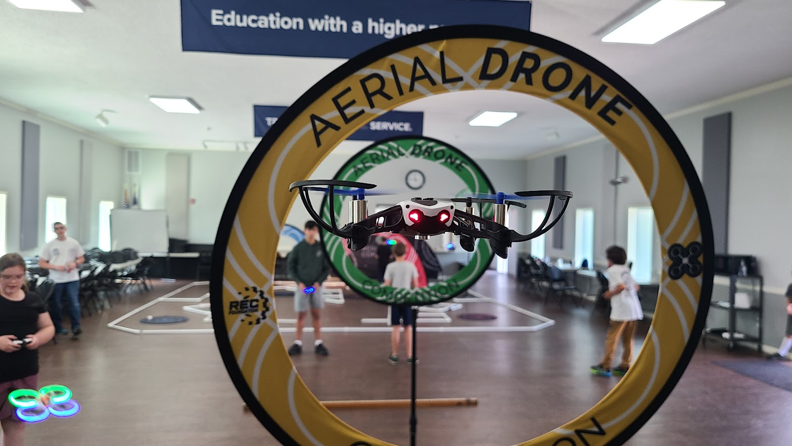 Drone flying through competition hoop with kids in background