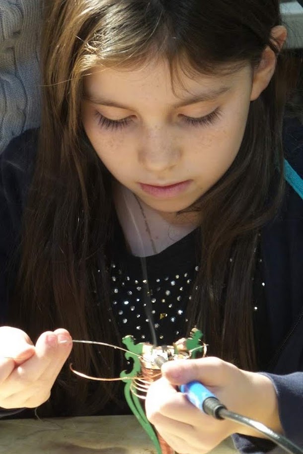 Girl soldering components on Tesla coil circuit